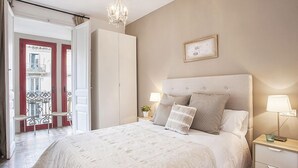 Un dormitorio con una cama grande, dos mesitas de noche, un candelabro y vistas al balcón exterior.