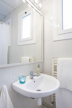 Une salle de bain avec un lavabo blanc, un miroir et un porte-serviettes.