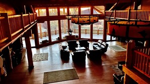 Un salon spacieux doté d’une grande fenêtre donnant sur une terrasse, d’un plancher en bois et d’une cheminée.