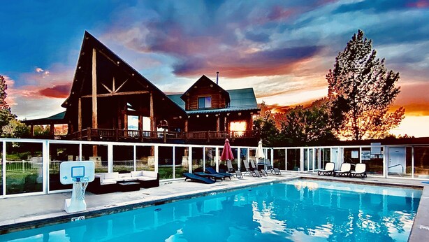 Une piscine avec des chaises longues et une maison en bois dotée d’un balcon.