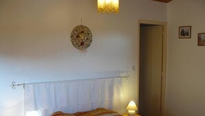 Ein Schlafzimmer mit einem Bett, zwei Nachttischlampen, einem Wandbild und einer Tür.