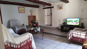 Ein Wohnzimmer mit Sofa, Sessel, Couchtisch, Fernseher und einer Treppe zu einer oberen Ebene.