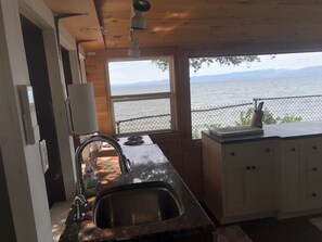 Cucina con lavello in acciaio inossidabile, mobili in legno e finestra con vista sull'acqua.