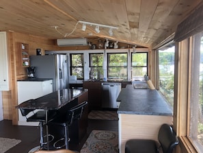 Una cucina moderna con isola centrale, elettrodomestici integrati e ampie finestre che offrono vista sull'esterno.
