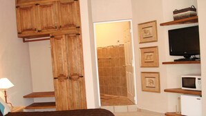 Une chambre à coucher comprenant un lit, une armoire en bois, un téléviseur et un espace douche.