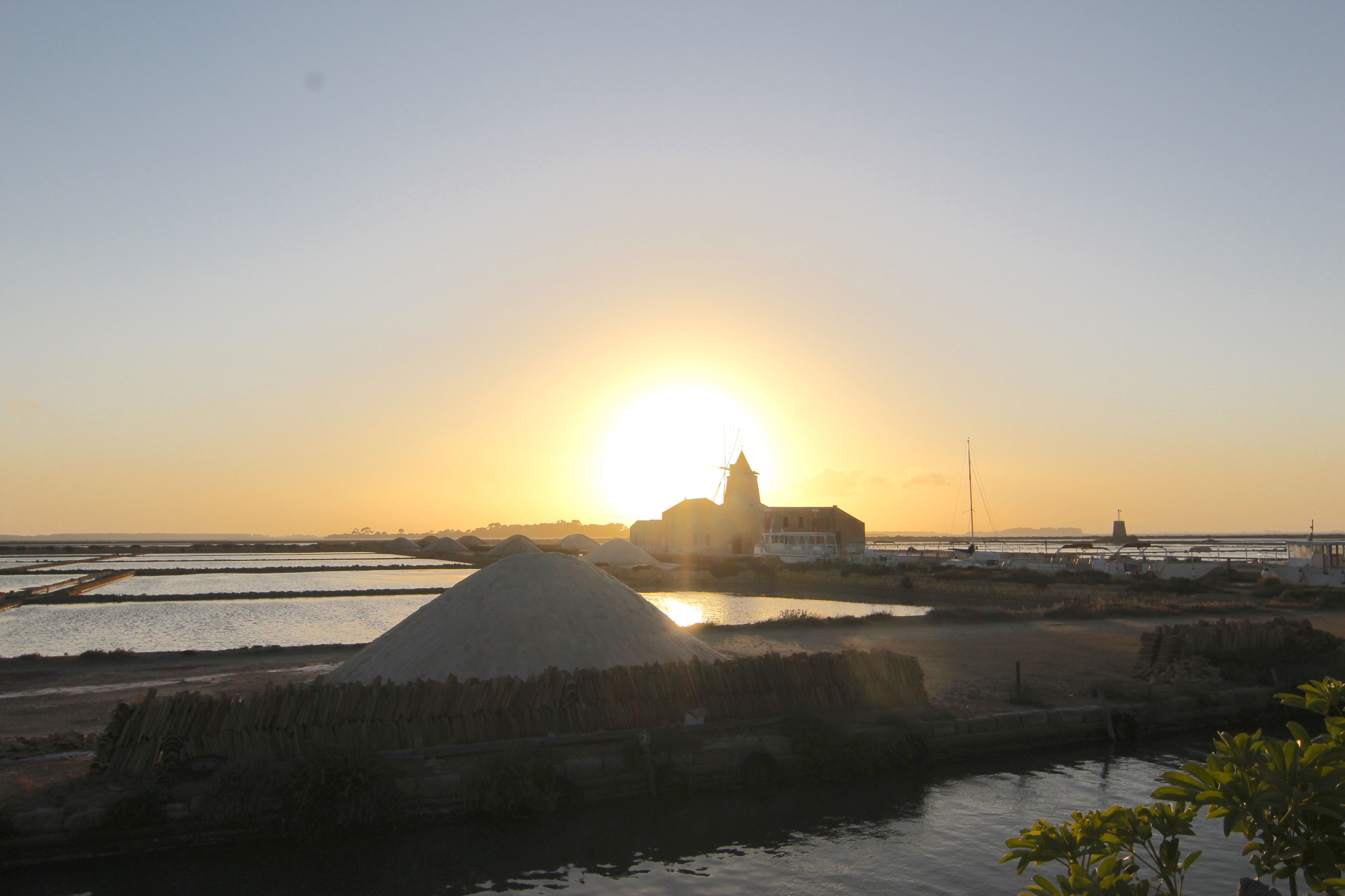 A coastal landscape with a building and water bodies during sunset.