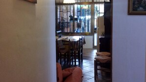 An interior with a dining area, a sofa, and a kitchen visible through an archway.