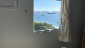 A bedroom with a large window offering a view of the sea and distant islands. - Penthouse with Pool, Barbecue and Wonderful Sea View (Florianópolis)