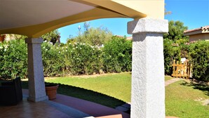 Un patio con columnas de piedra, macetas de terracota y césped bien cuidado.