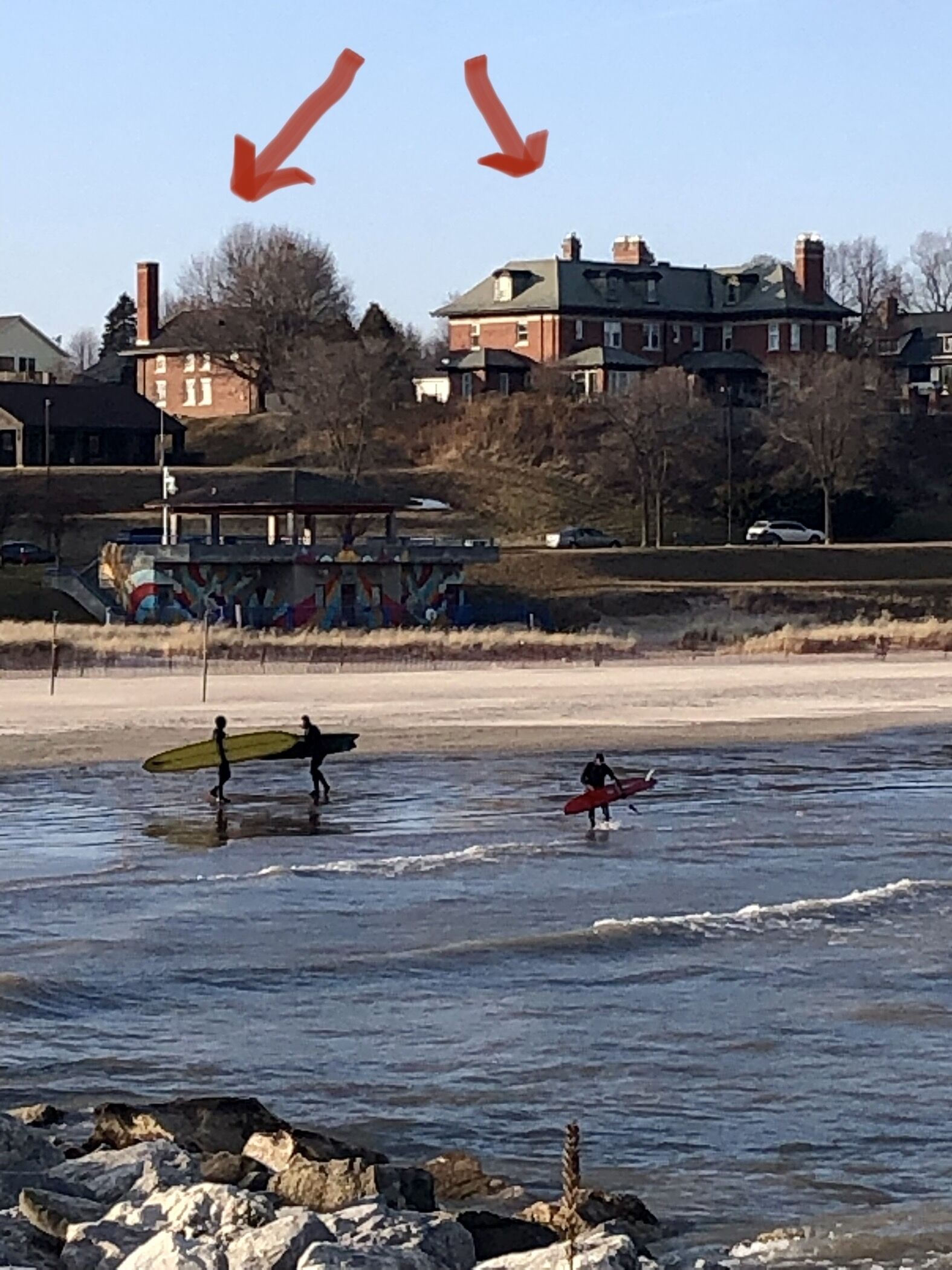 A beach with surfers and a building in the background.