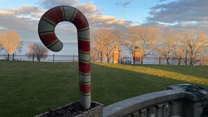 Un parc amb una gran escultura de canya de sucre, una barana de pedra i vistes a arbres sense fulles i un cos d'aigua.