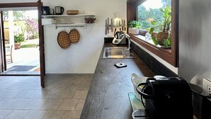 Une cuisine moderne dotée d’une grande fenêtre, d’appareils électroménagers en acier inoxydable et offrant une vue sur la verdure environnante.