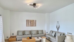 A modern living room with a grey sofa, a wooden coffee table, and a dreamcatcher on the wall.