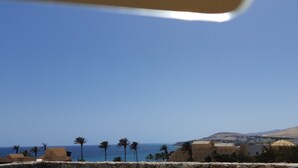 A coastal view with a clear sky, palm trees, and a distant mountain. - Excl. new villa with herlichen panoramic sea views over the Atlantic Ocean off Costa Calma (Costa Calma)