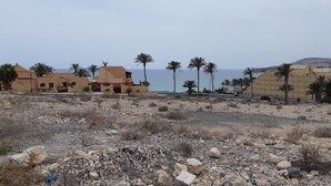 A coastal area with buildings, palm trees, and a rocky terrain. - Excl. new villa with herlichen panoramic sea views over the Atlantic Ocean off Costa Calma (Costa Calma)