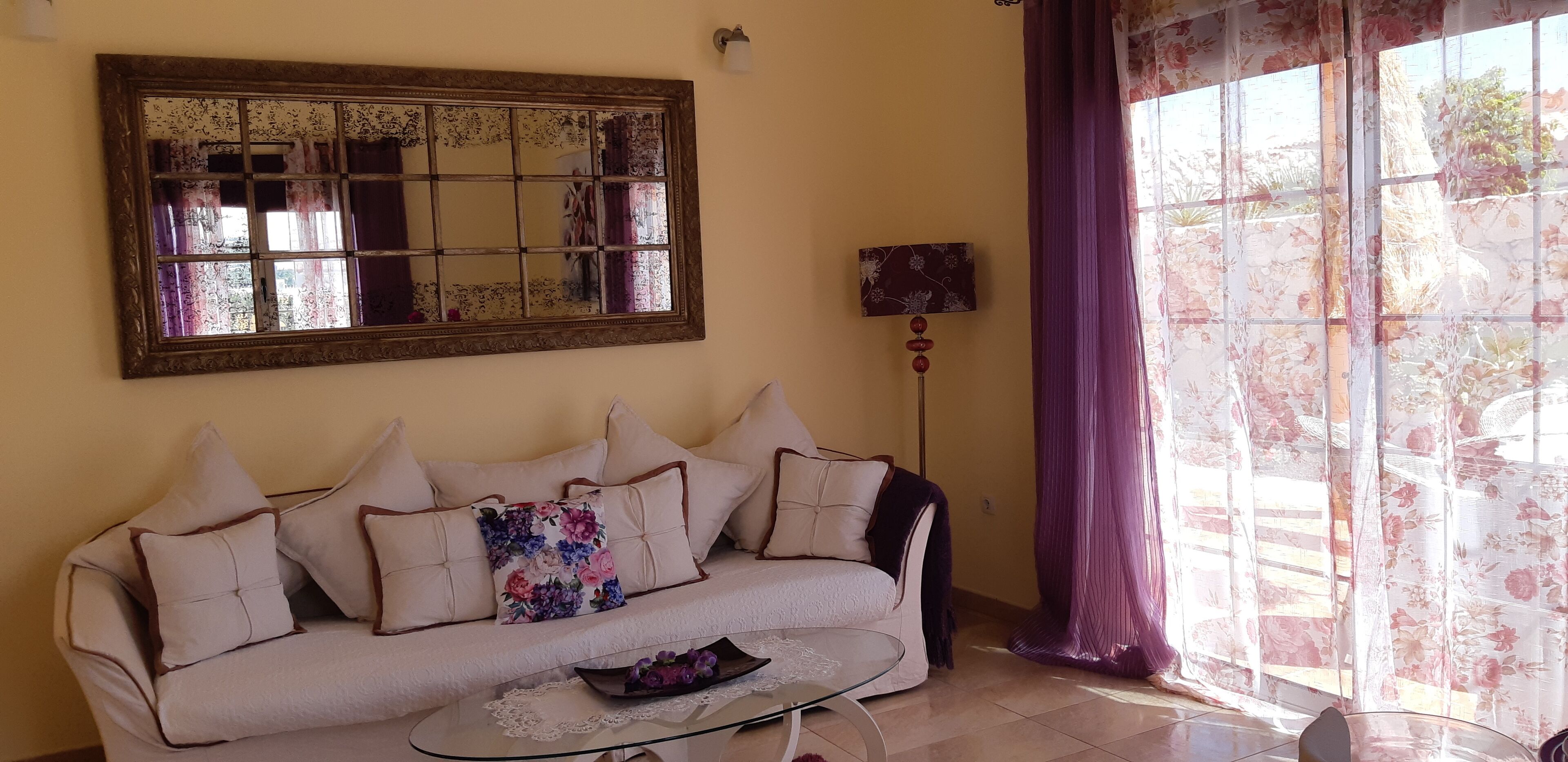 Una sala de estar con sofá, una mesa de centro, un espejo y una lámpara.