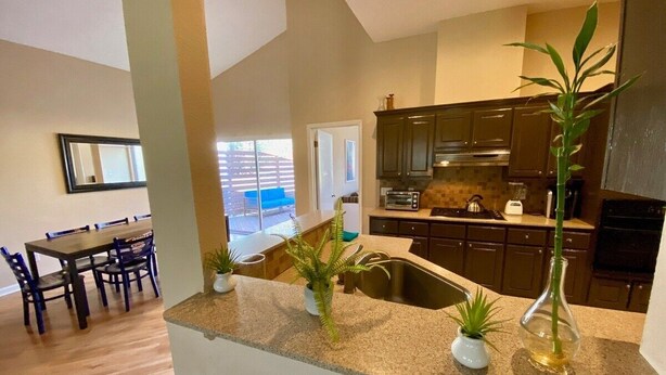 A modern kitchen with granite countertops, dark cabinets, and a large window.