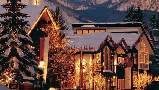 Eine verschneite Berglandschaft mit einem Chalet, geschmückt mit Weihnachtsbeleuchtung und Dekorationen.