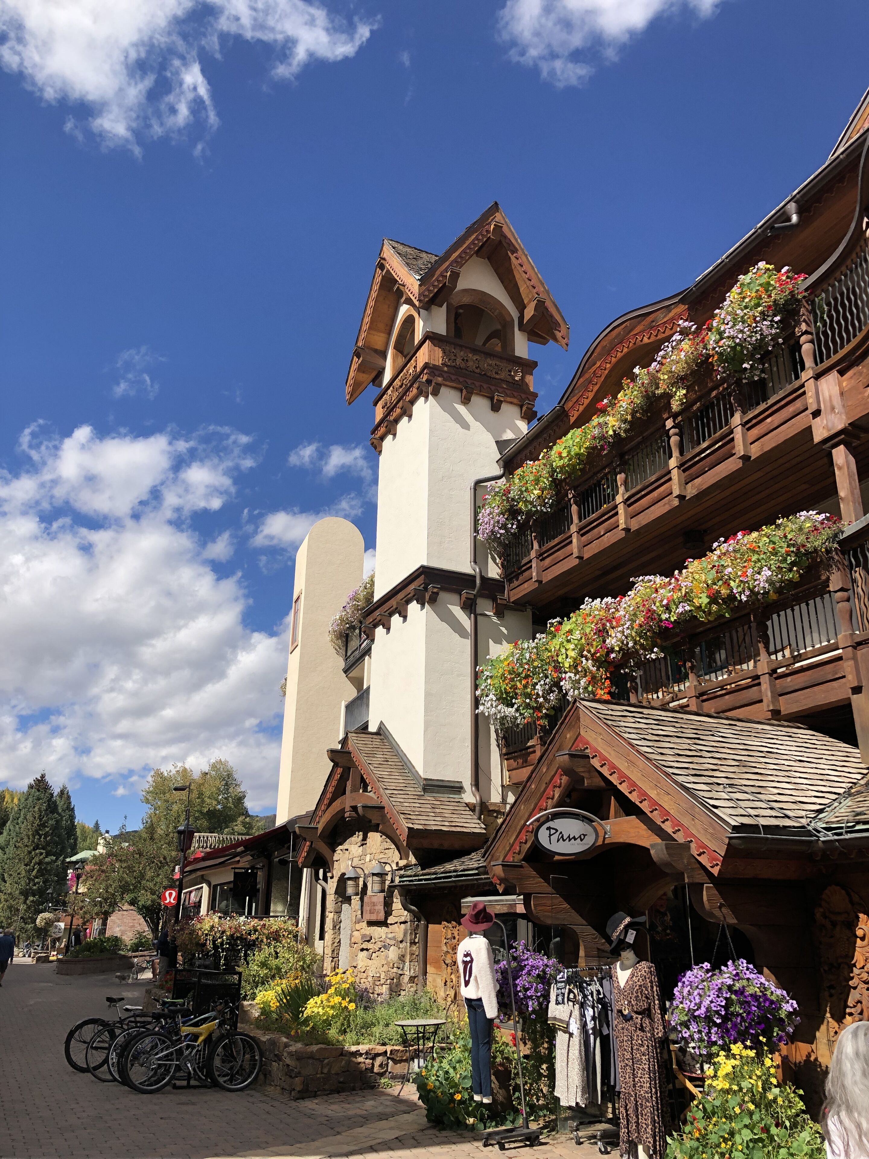 A traditional chalet with a tower, wooden balconies with flower boxes, and a sign reading "Panorama".