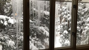 Ein Zimmer mit großem Fenster mit Blick auf einen verschneiten Wald.