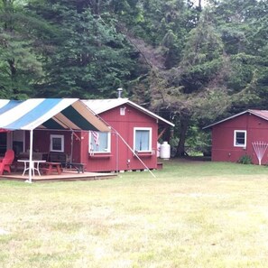 Une cabane rouge avec un auvent rayé et une table de pique-nique.