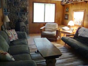 Un salon chaleureux avec une cheminée en pierre, une grande fenêtre et un coin salon confortable.