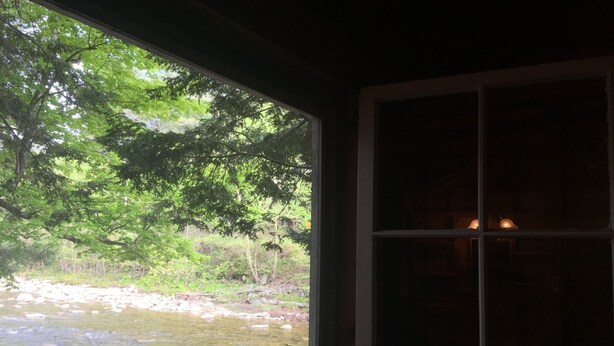 A window with a view of a natural landscape, including trees and a body of water.