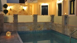 A swimming pool area with stone tiles, a lounge chair, and a candle.