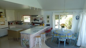 A kitchen with a central island, a dining area with a table and chairs, and a view of the outdoors through a window. - A Relaxing Place To Have Fun In The Sun!  (Yakima)