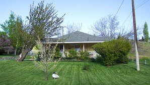 A house with a well-maintained lawn, a small tree, and a bird on the grass. - A Relaxing Place To Have Fun In The Sun!  (Yakima)