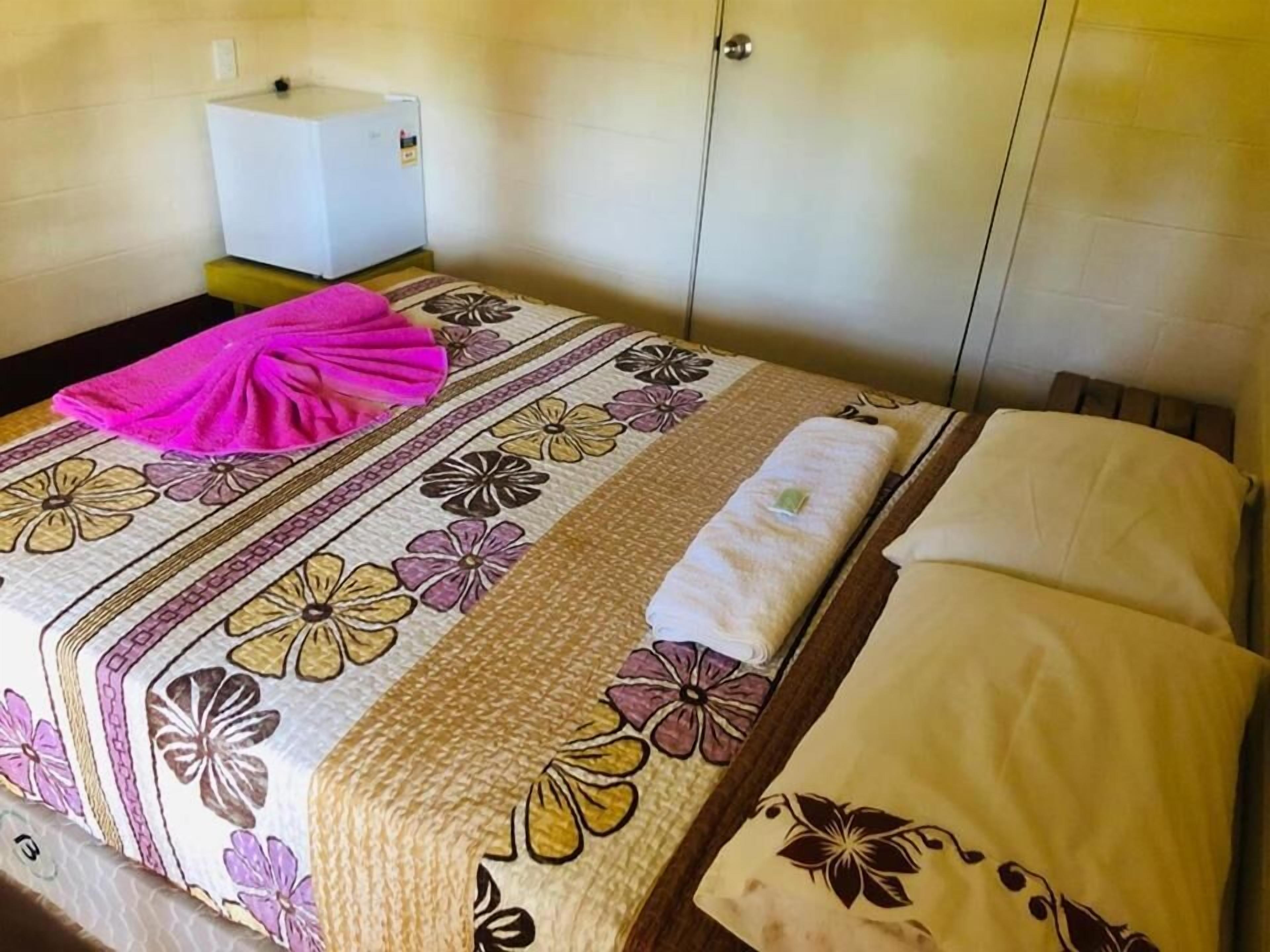 Una habitación de hotel con una cama, una mesita de noche y un pequeño armario blanco.