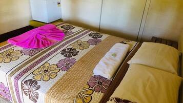 Una habitación de hotel con una cama, una mesita de noche y un pequeño armario blanco.