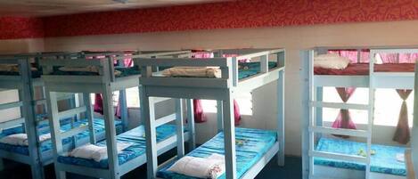 Bunk beds in a room with a patterned wall and a ceiling fan.