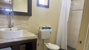 A bathroom with a white sink, a toilet, and a shower curtain. - Transit Motel - Hostel (Mulifanua)