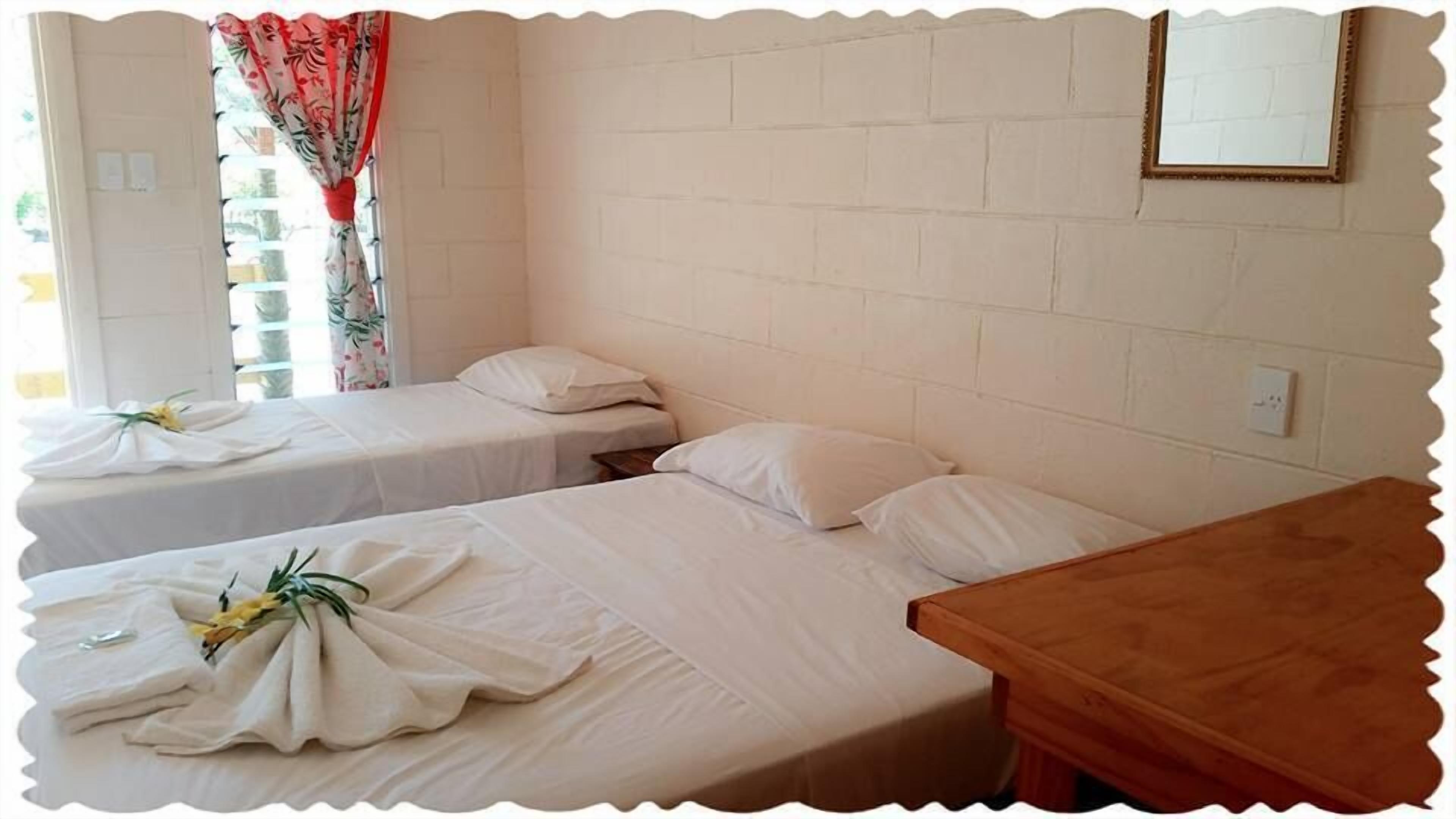 Een kamer met twee eenpersoonsbedden, een houten tafel en een spiegel aan de muur.