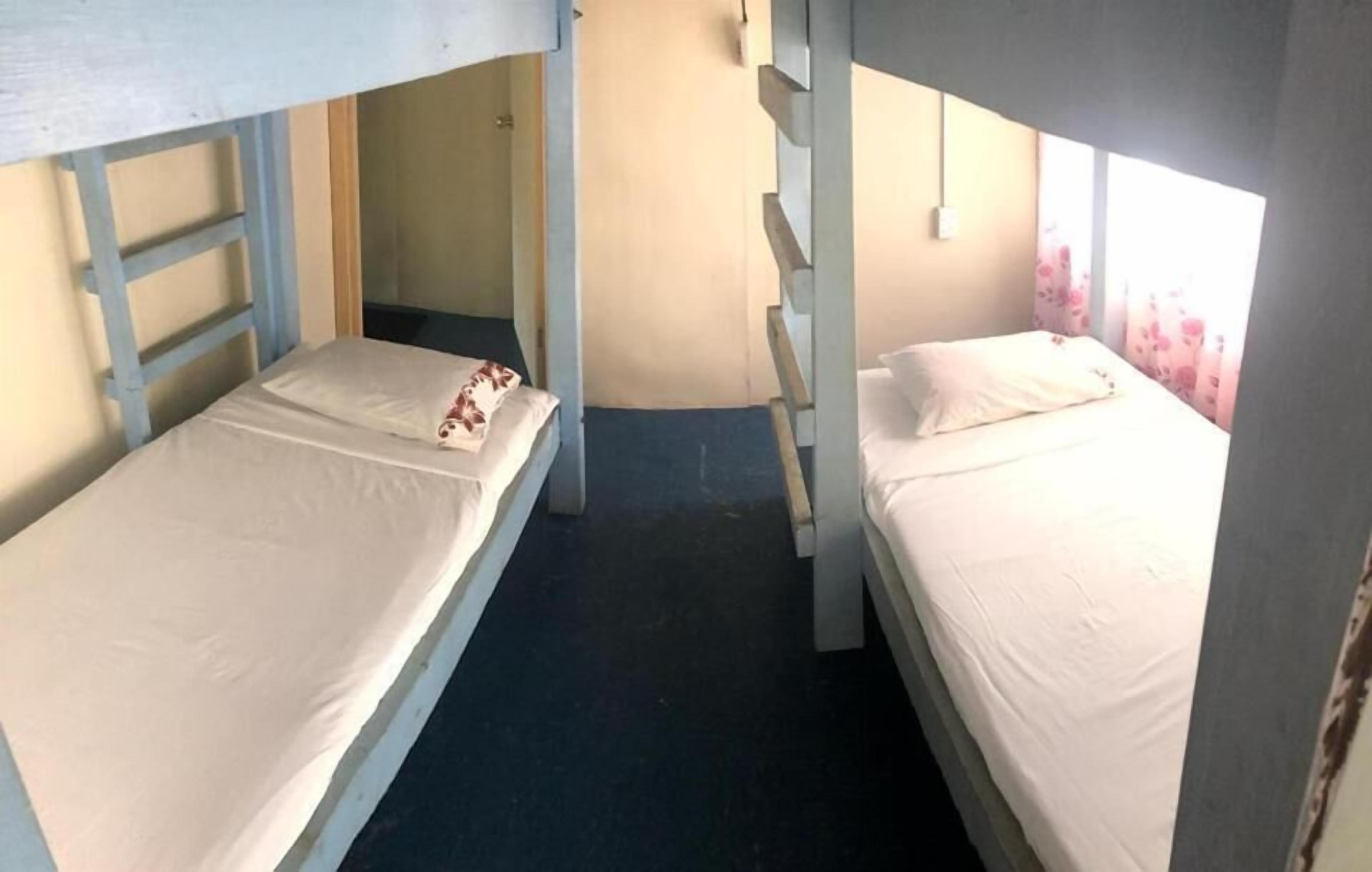 A bunk bed room with two beds, a ladder, and a window with floral curtains.