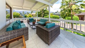 A covered outdoor seating area with wicker furniture and a view of the surrounding landscape.