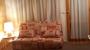 Ein Schlafzimmer mit Bett, Vorhängen, einem Nachttisch und einer Lampe.