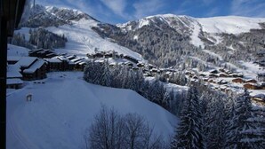Ein verschneites Bergdorf mit Holzhäusern und einer Skipiste.