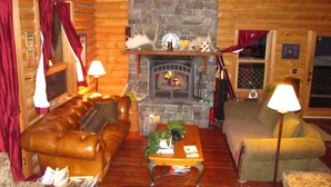 A cozy log cabin interior with a stone fireplace, leather sofas, and a wooden coffee table. - Great All Season Log House in Alpine,WY (Alpine)