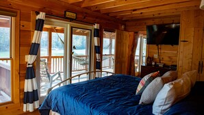 Een chalet met een bed, een televisie en een balkon met een hangmat.