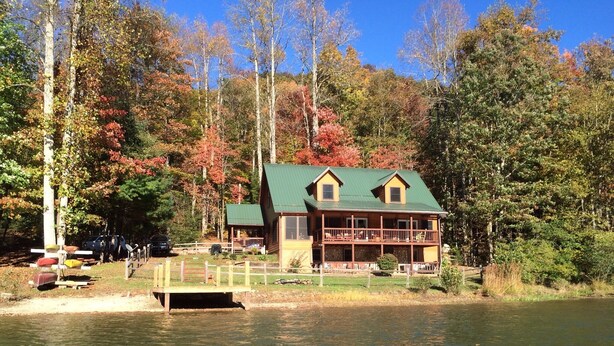 Een chalet met een groen dak, een stenen fundering en een houten terras.