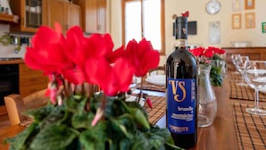 Uma garrafa de VS Brunello sobre uma mesa com flores vermelhas e copos.