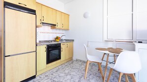 Una cocina moderna con armarios de madera, horno negro y una mesa de comedor blanca con dos sillas.