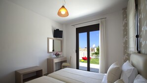 A bedroom with a bed, a bedside table, a mirror, and a view of the outdoors. - Villas For Family Holidays (Rethymno)