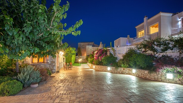 A paved pathway leading to a building with a stone wall and potted plants. - Villas For Family Holidays (Rethymno)
