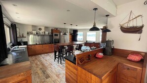 A spacious kitchen with wooden cabinets, a central island, and a hanging light fixture. - L'Abri des flots Seaside Villa in Bonifacio, L'Abri des flots (Bonifacio)