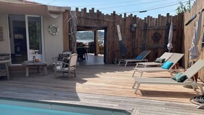 A wooden deck with a pool, lounge chairs, and a rustic wooden wall. - L'Abri des flots Seaside Villa in Bonifacio, L'Abri des flots (Bonifacio)