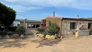 A two-story stone house with a red-tiled roof, a gravel driveway, and a small garden with rocks and plants. - L'Abri des flots Seaside Villa in Bonifacio, L'Abri des flots (Bonifacio)