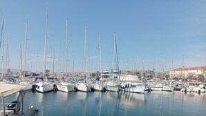 Un port de plaisance où sont amarrés de nombreux voiliers, avec une eau calme et des bâtiments en arrière-plan.